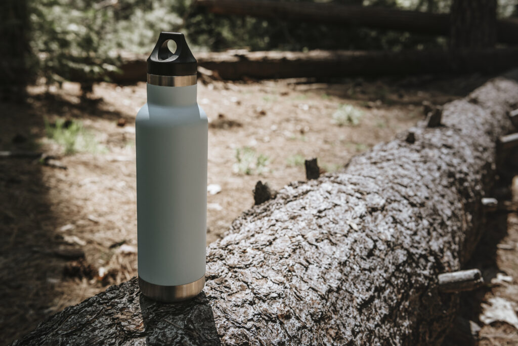 an insulated thermos for camping on a tree trunk.