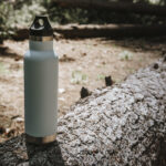 an insulated thermos for camping on a tree trunk.