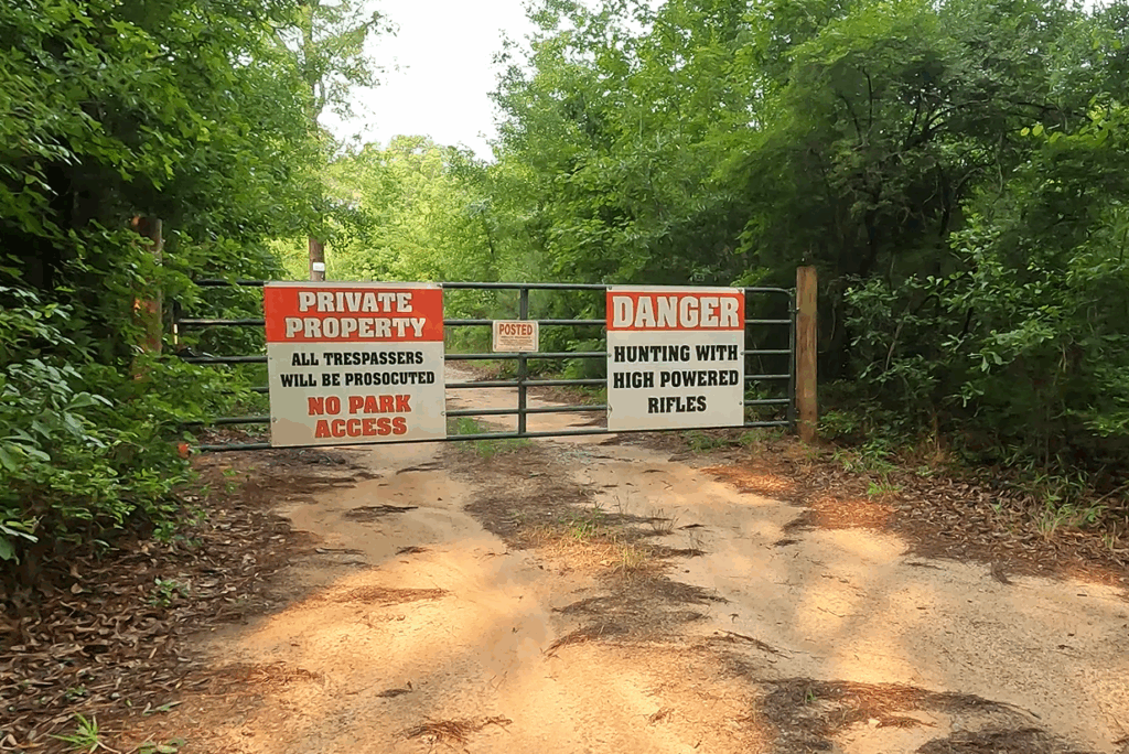 Massive no trespassing signs on a fence at Congaree National Park.