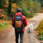 man hiking on trail in fall with dog.