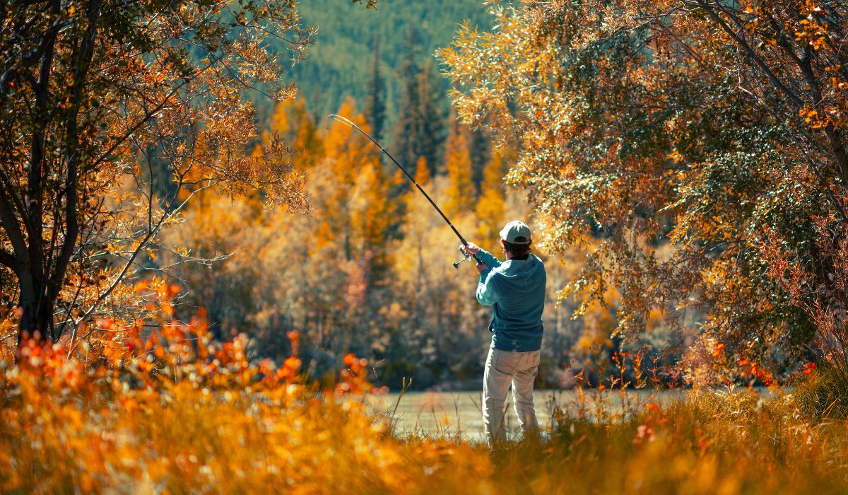 A person fishing on a pond in the fall.