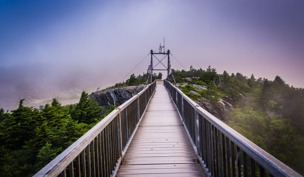 The Mile-High Swinging Bridge at Grandfather Mountain in North Carolina, shrouded in fog with a purple hue.