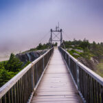 The Mile-High Swinging Bridge at Grandfather Mountain in North Carolina, shrouded in fog with a purple hue.